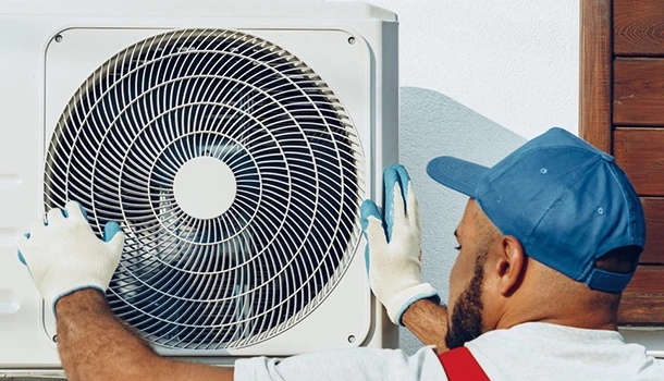 Technician performing AC repair on an outdoor unit.