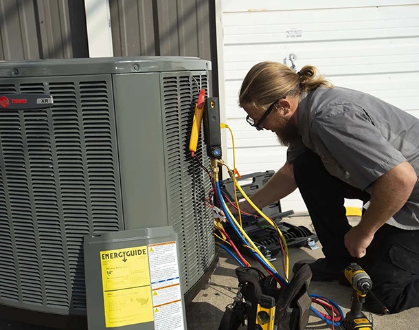 HVAC technician performing AC maintenance on an outdoor unit.